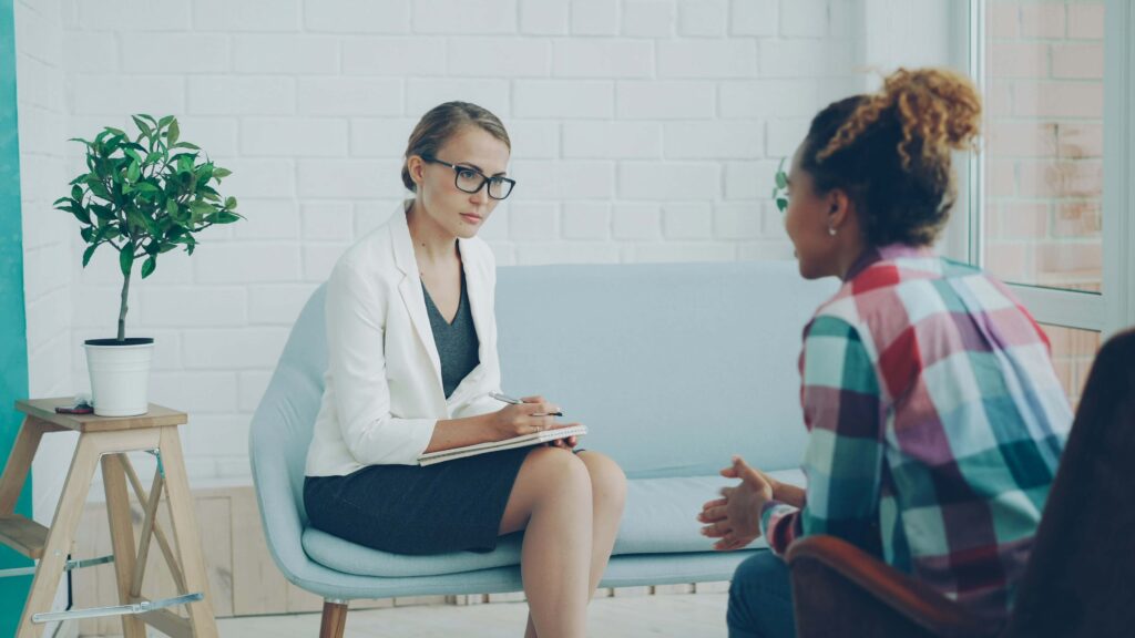 Two women sitting across from each other in a therapy session.